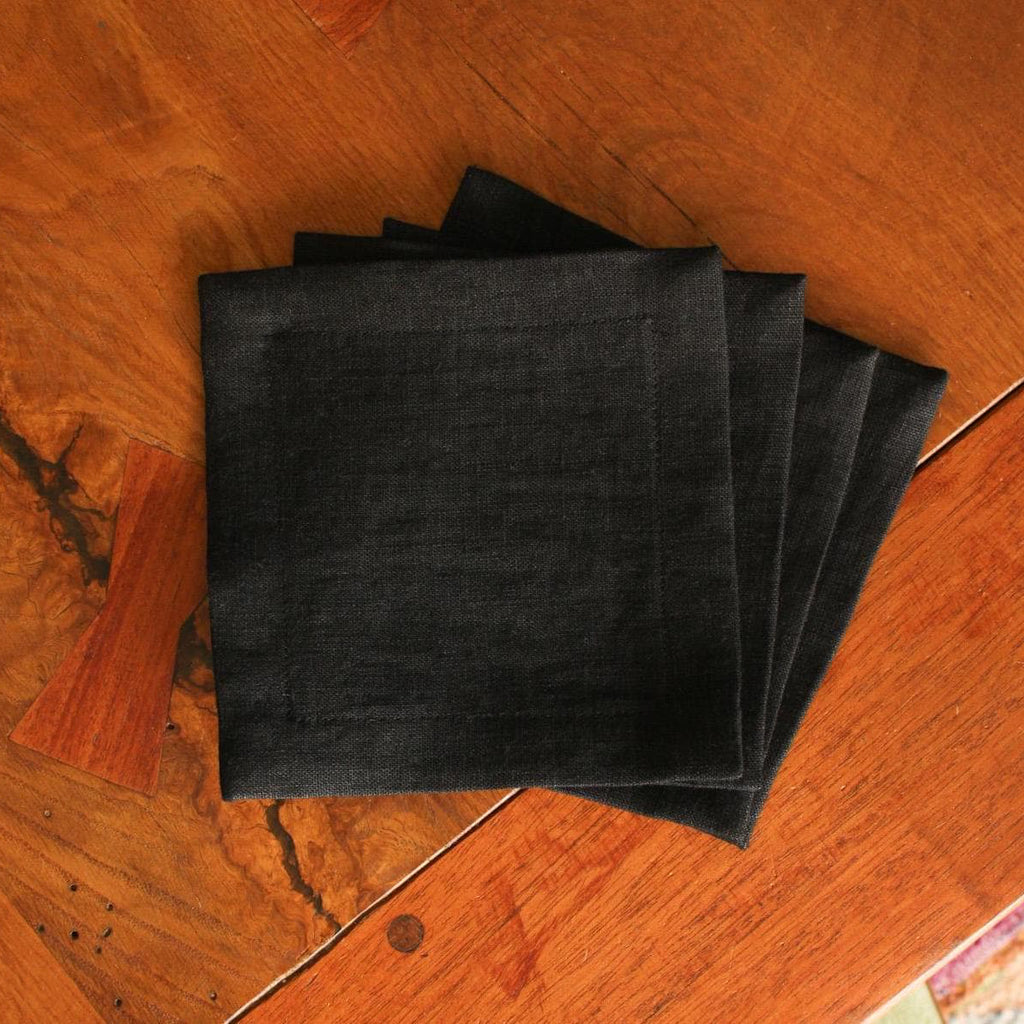 Four black napkins on a wooden surface