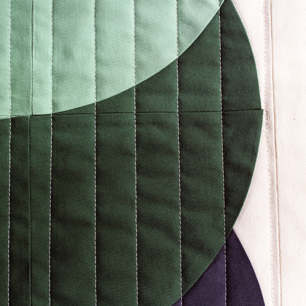 Close-up of a quilt with green fabric and visible stitching