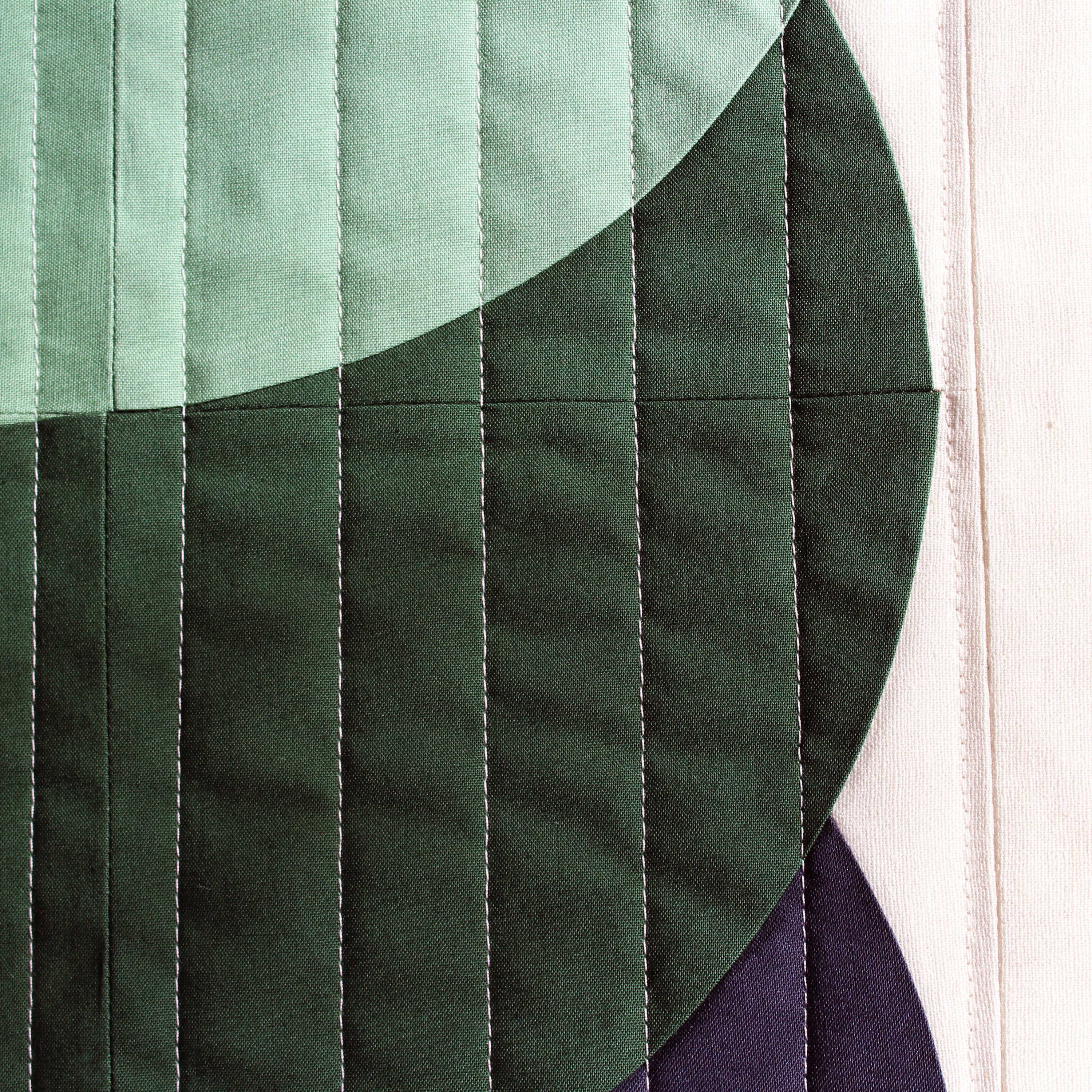 Close-up of a quilt with green fabric and visible stitching