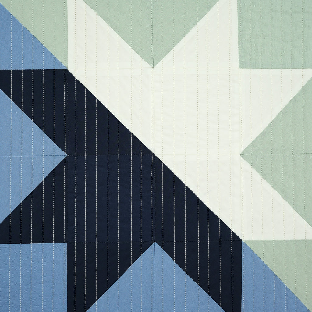 Geometric quilt pattern with triangles in blue, green, and white.