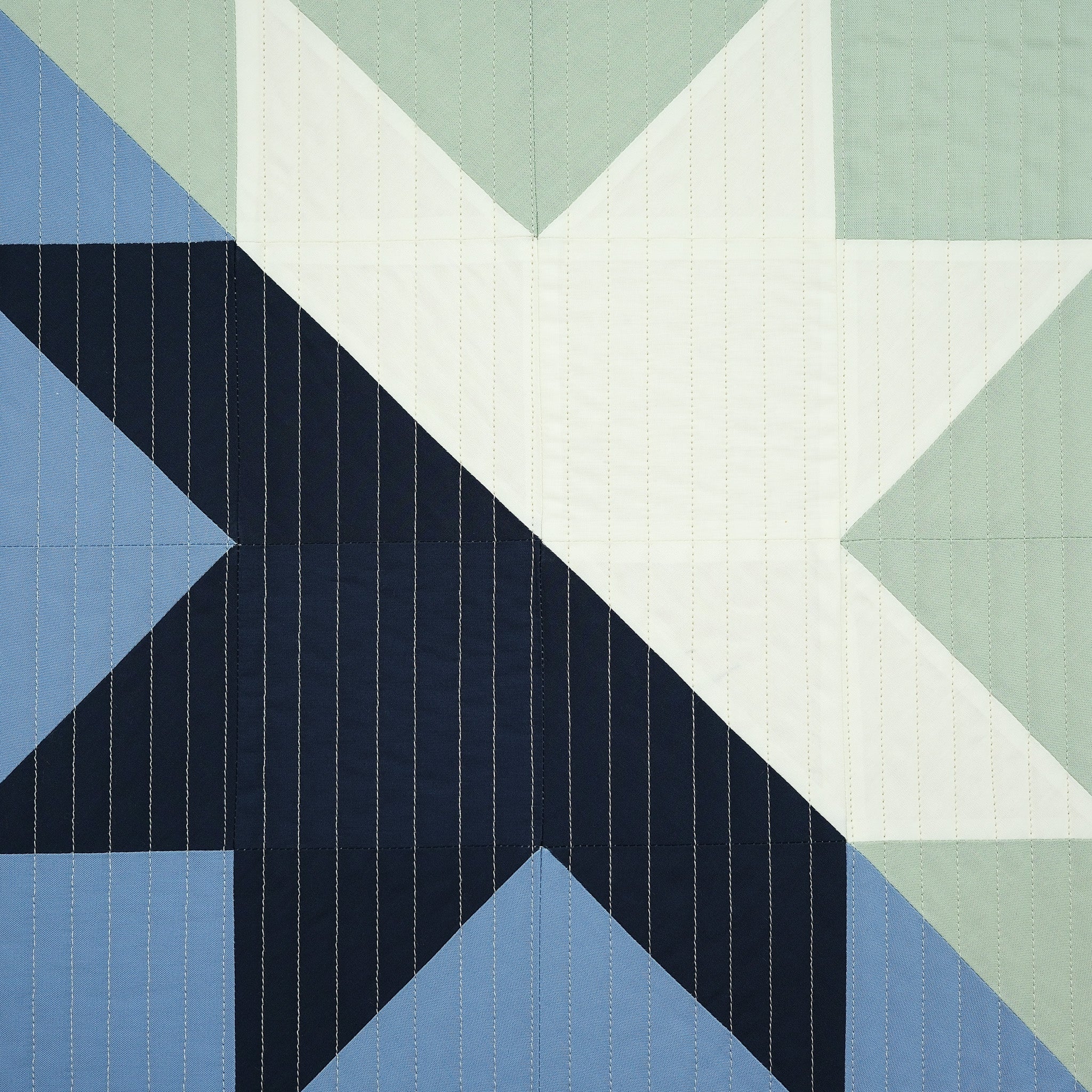 Geometric quilt pattern with triangles in blue, green, and white.
