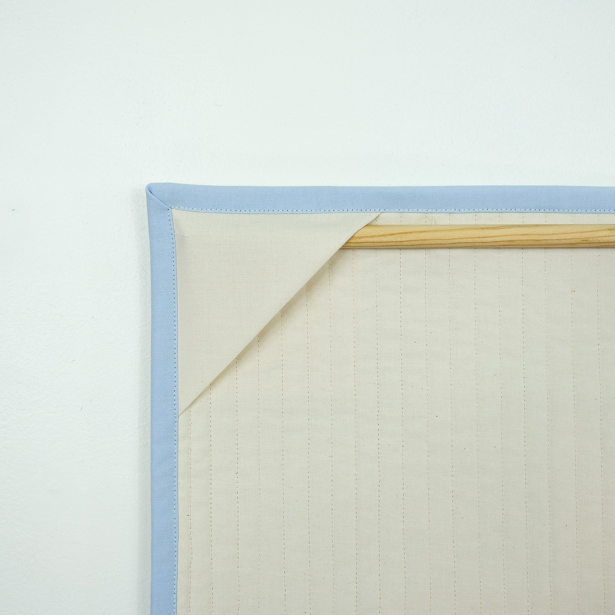 Backing of hanging quilt showing corner tabs with a wooden dowel