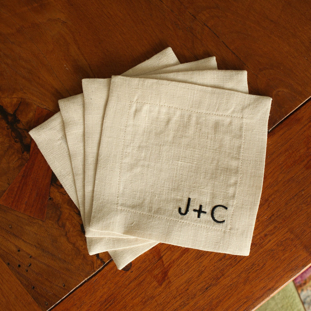 Stack of white napkins with initials 'J+C' on a wooden surface