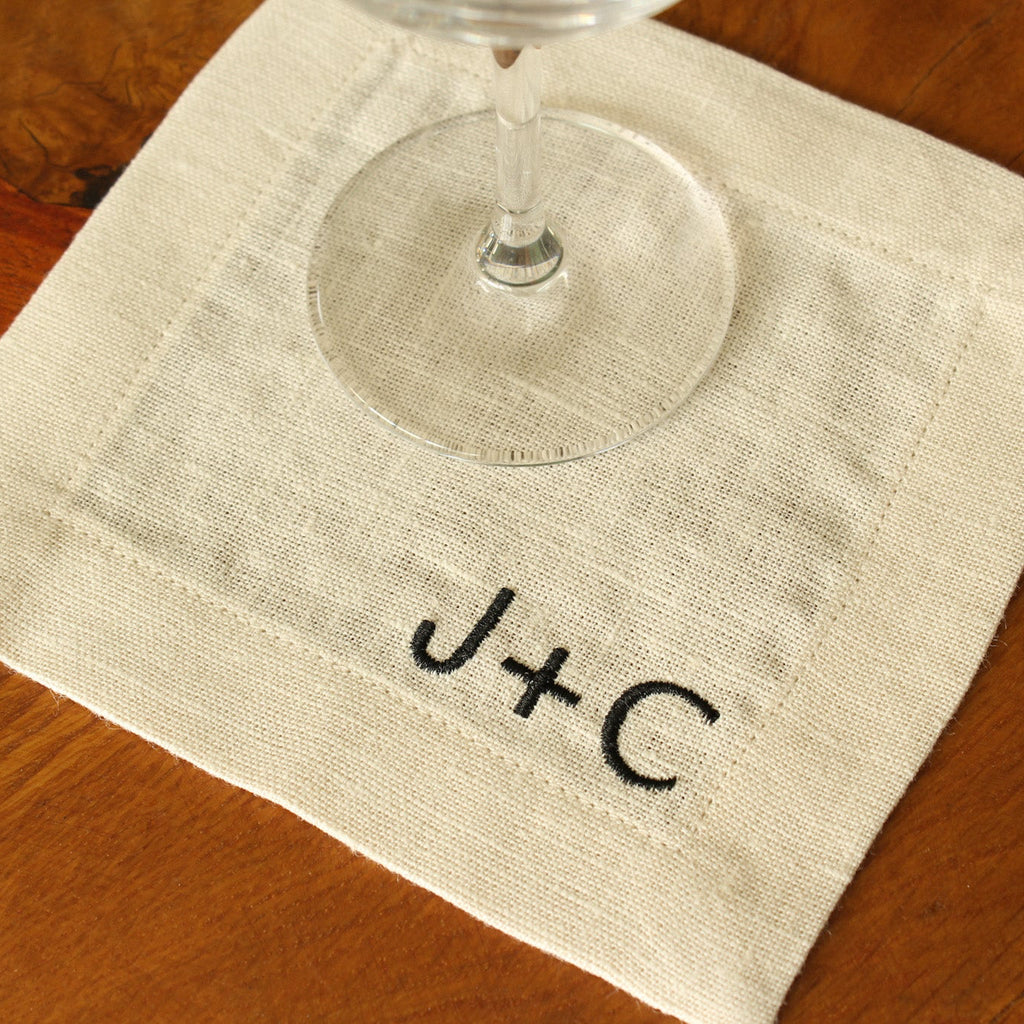 Wine glass on a cream white napkin with initials 'J+C' on a wooden surface
