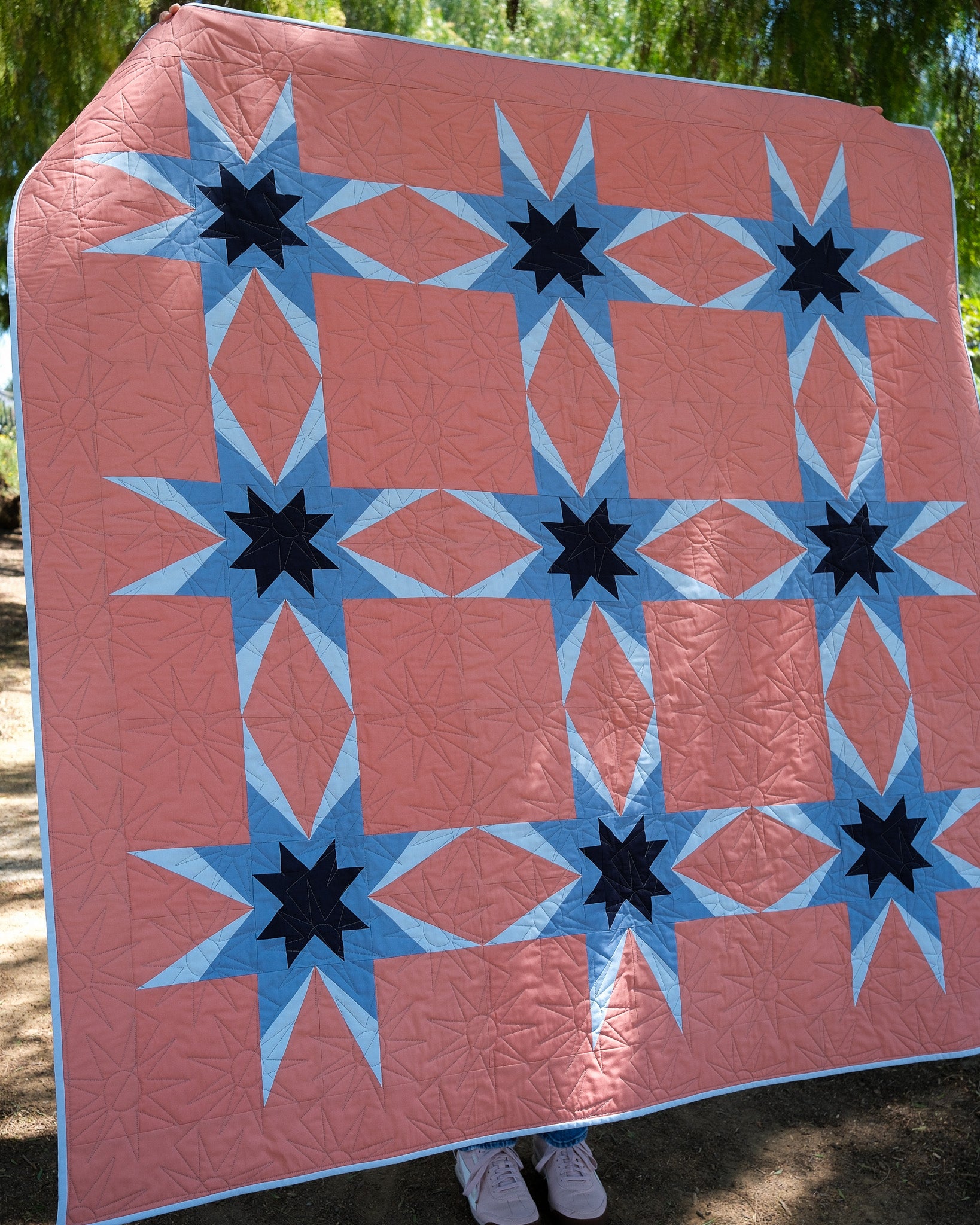 Quilt with star and diamond pattern displayed outdoors