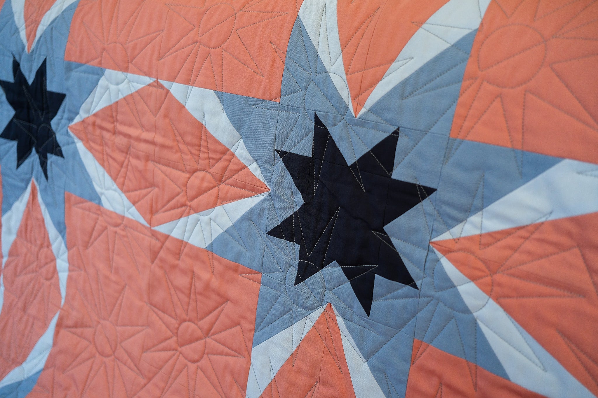 Quilt with star patterns in red, blue, and black on a star-shaped background