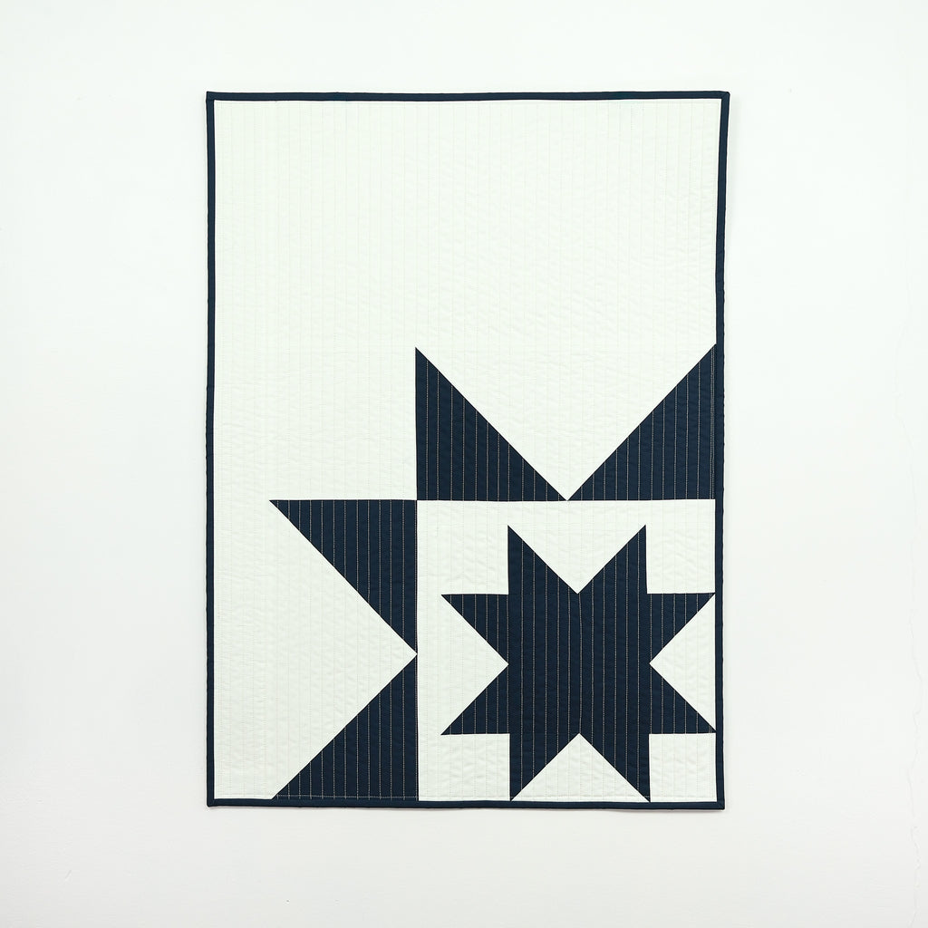 Navy star patterned quilt on a white background
