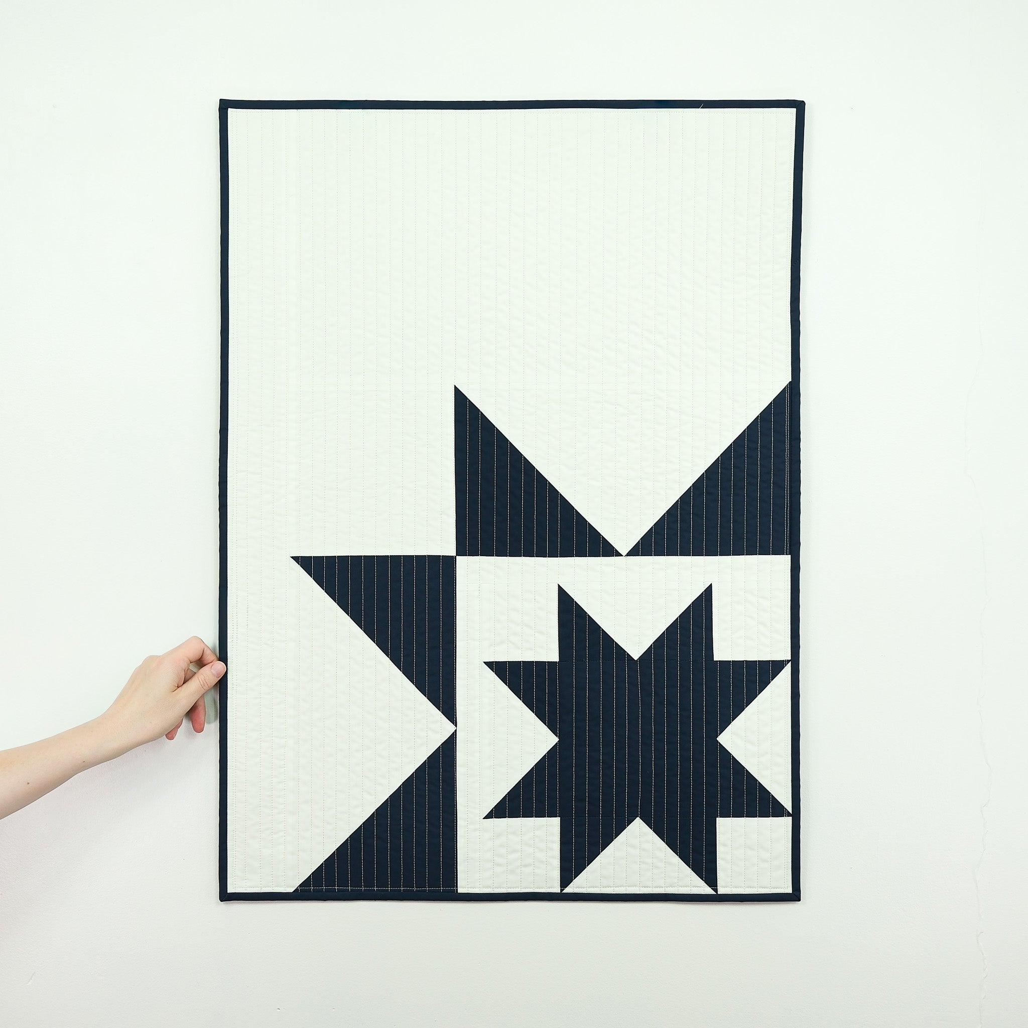Star-shaped quilt held by a hand on a white background