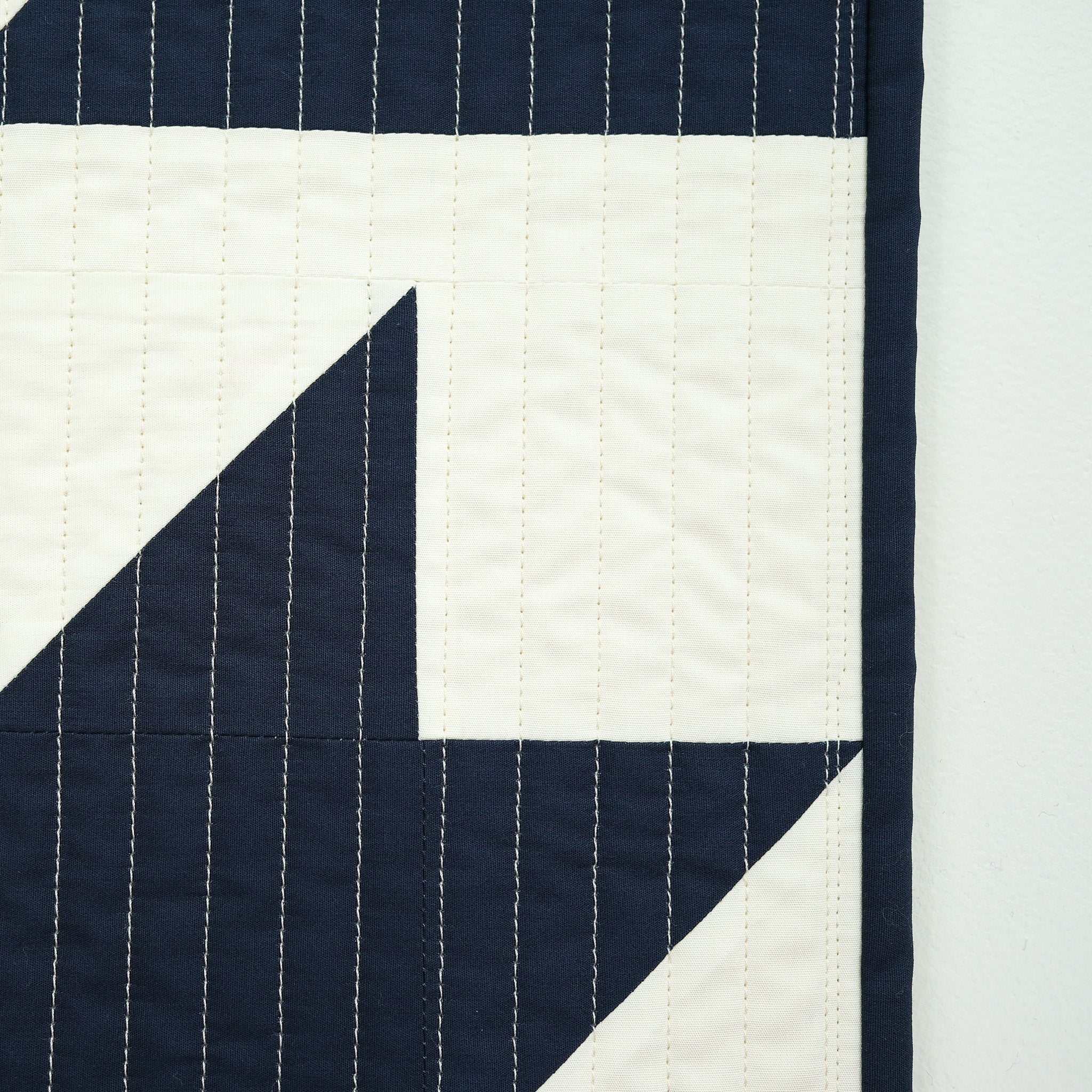 Navy and white quilt with geometric pattern on a light gray background