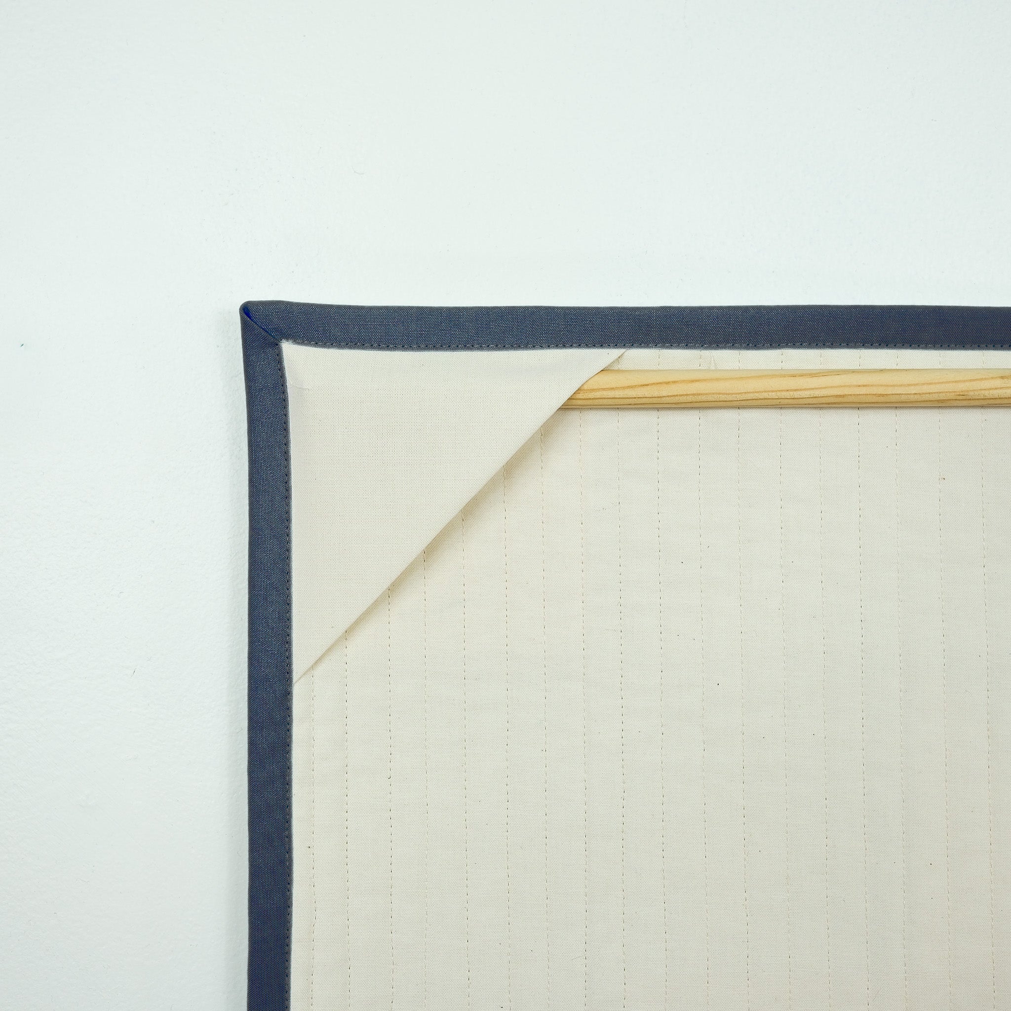 Backing of hanging quilt showing corner tabs with a wooden dowel