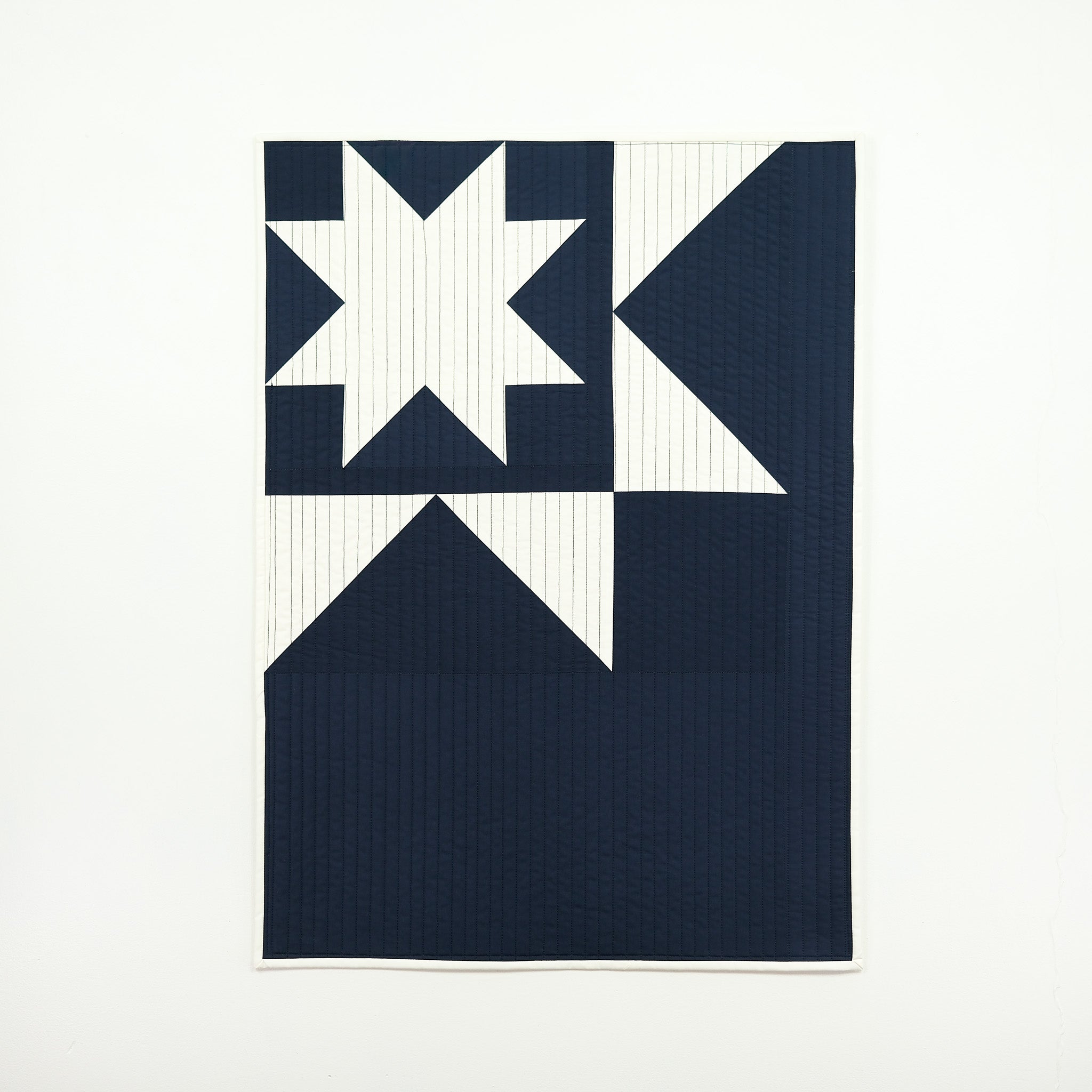 Navy blue and white quilt with geometric pattern on a white background