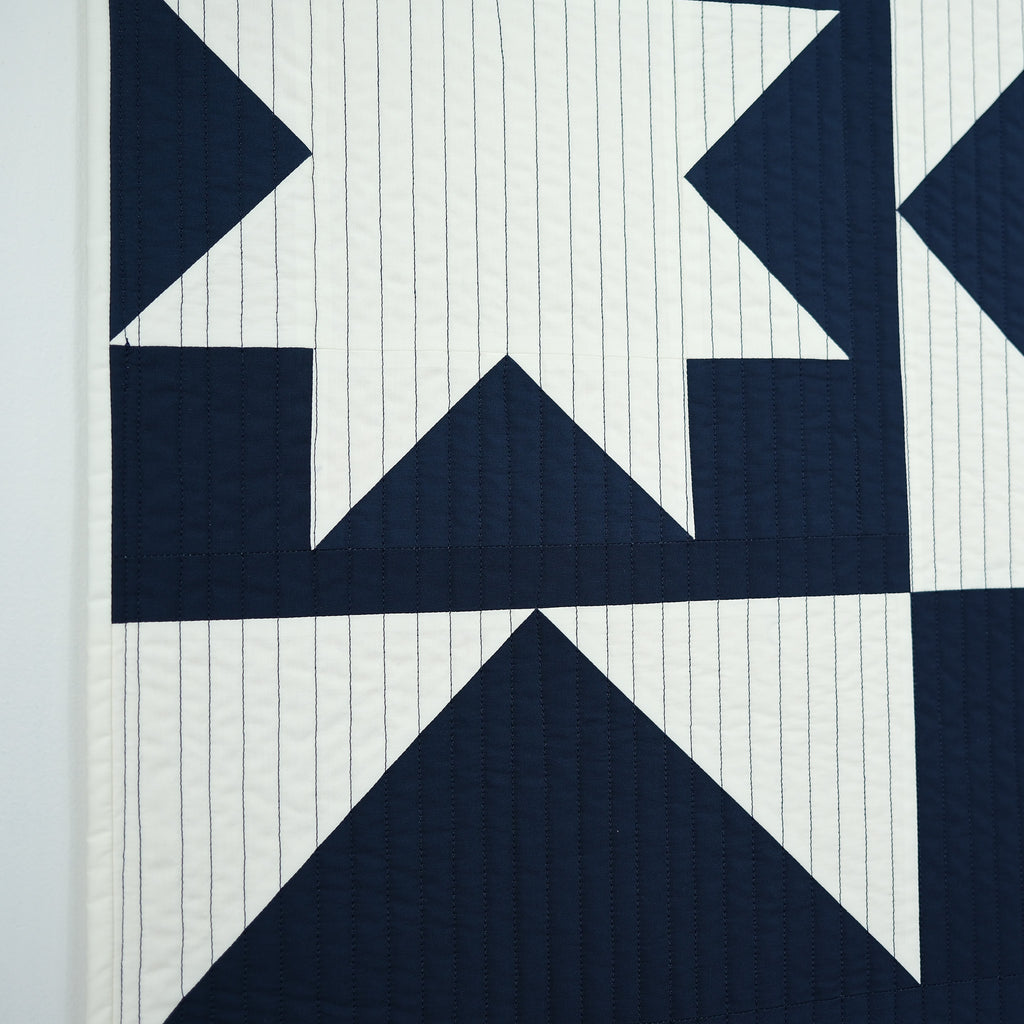Navy blue geometric quilt pattern on a white background