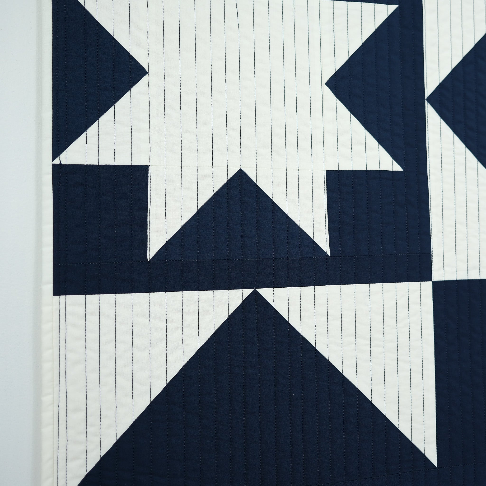 Navy blue geometric quilt pattern on a white background