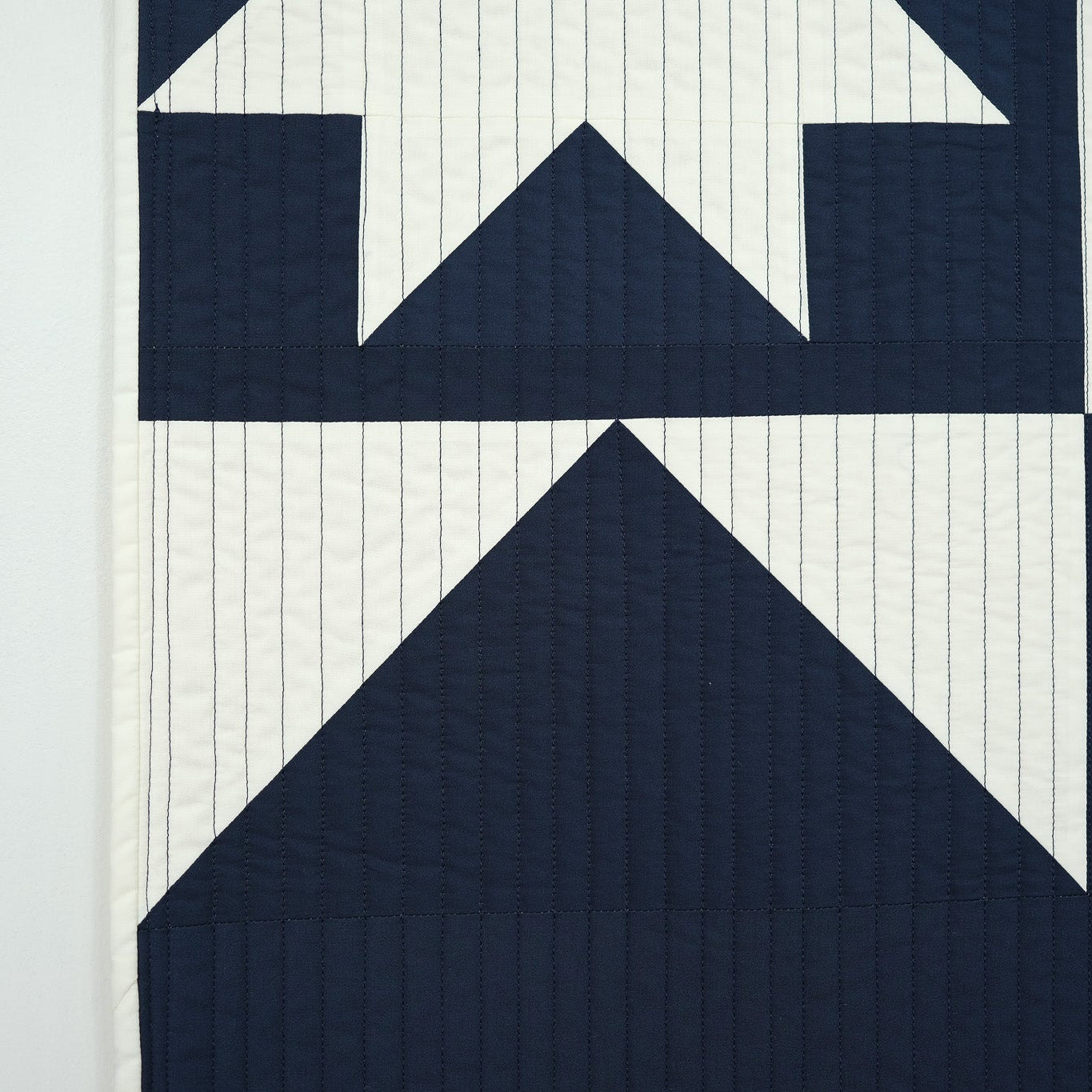 Navy blue and white quilt with geometric pattern on a light gray background