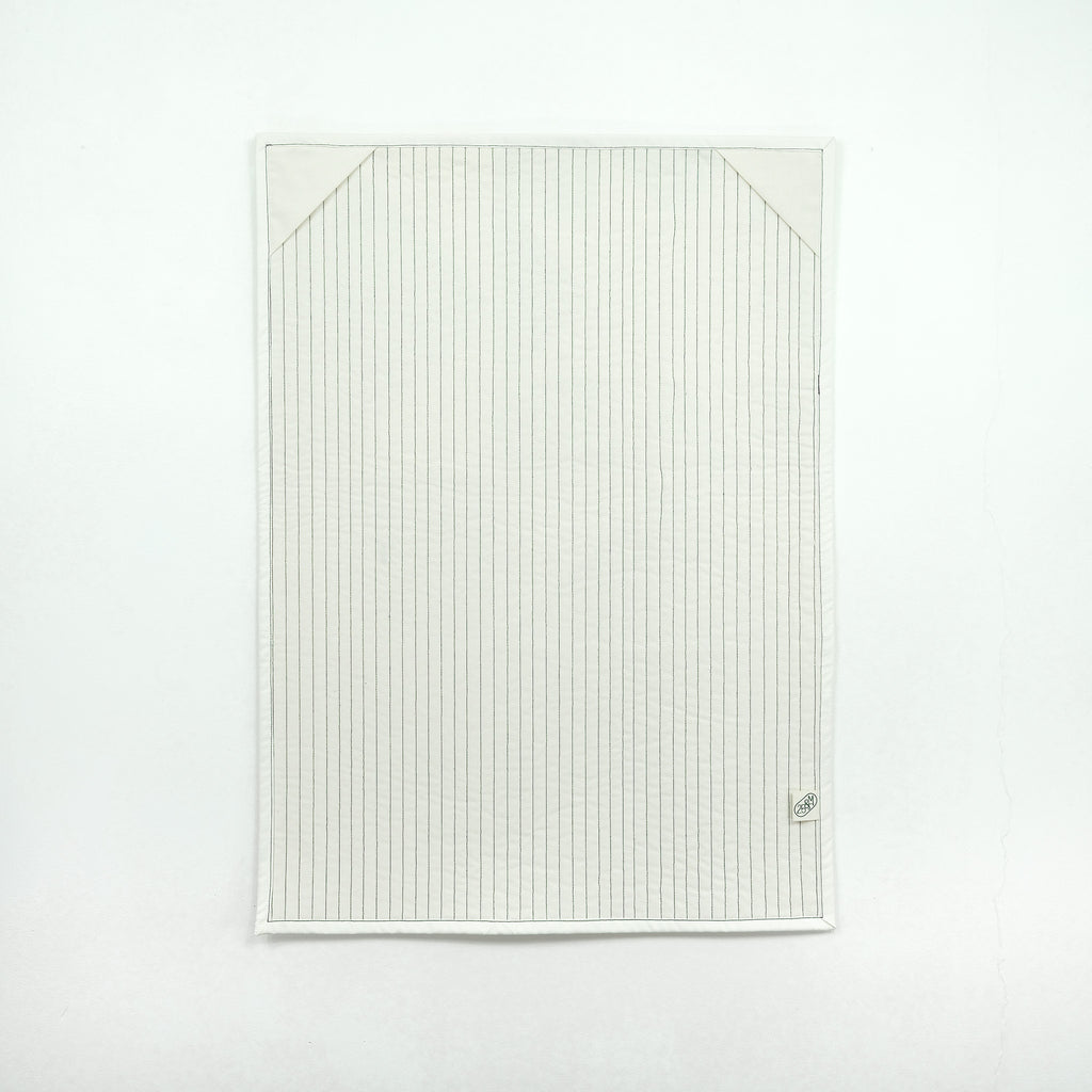 Backing of quilt showing white fabric with corner hanging tabs