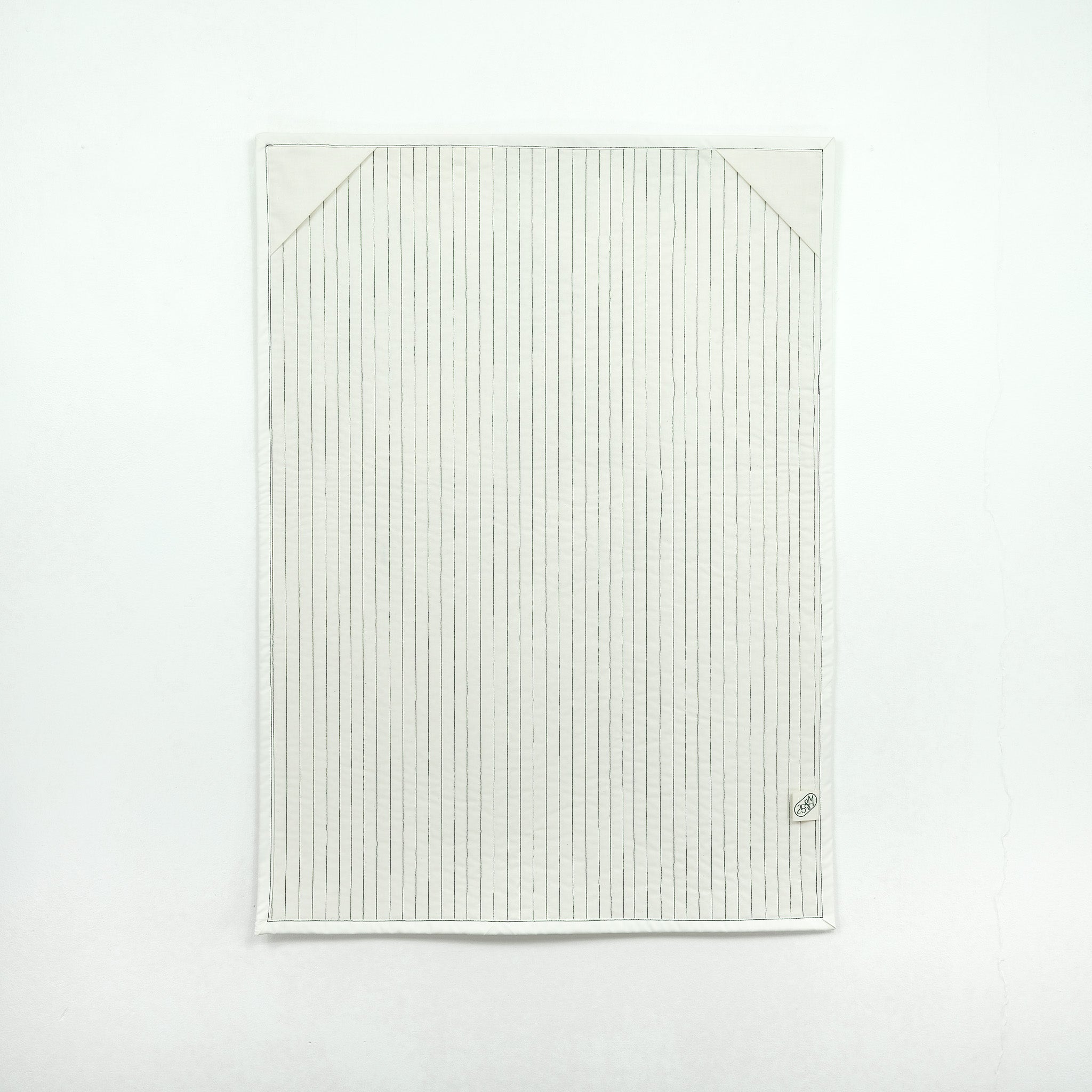 Backing of quilt showing white fabric with corner hanging tabs