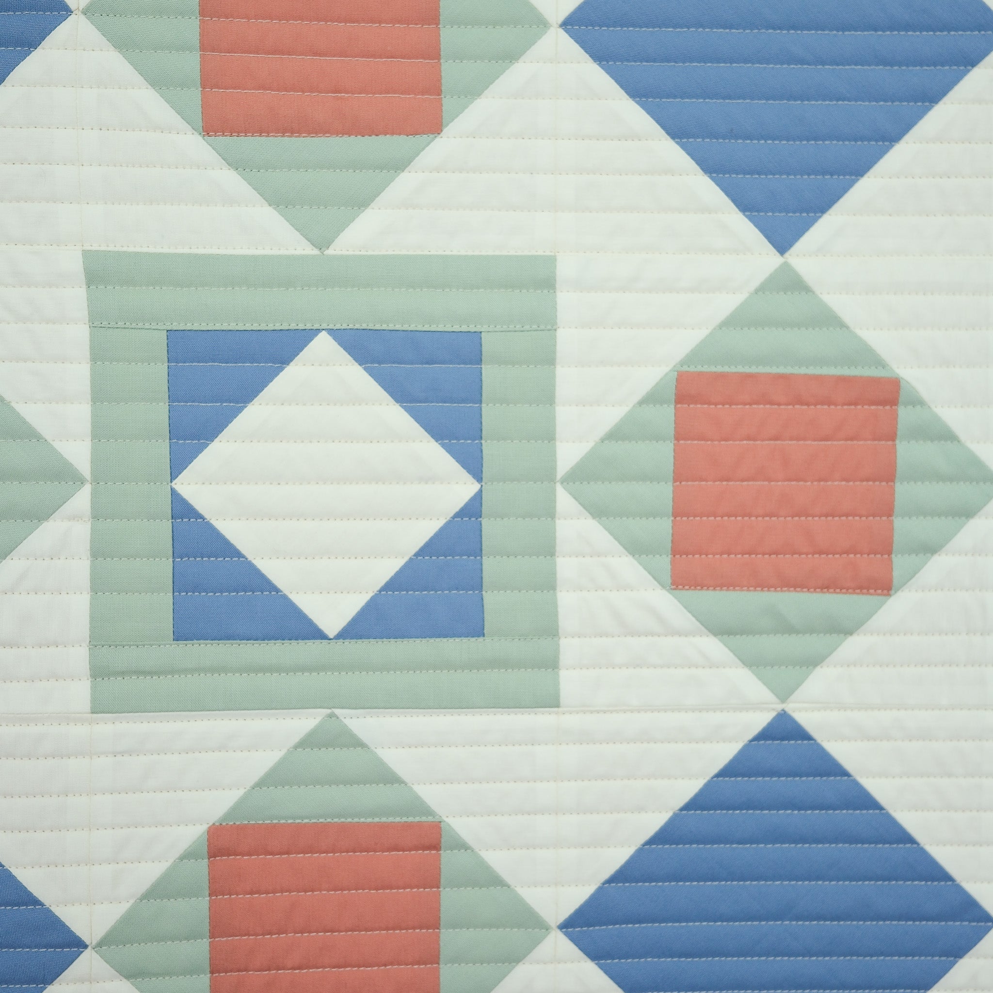 Quilt with geometric pattern featuring squares and diamonds in pastel colors.