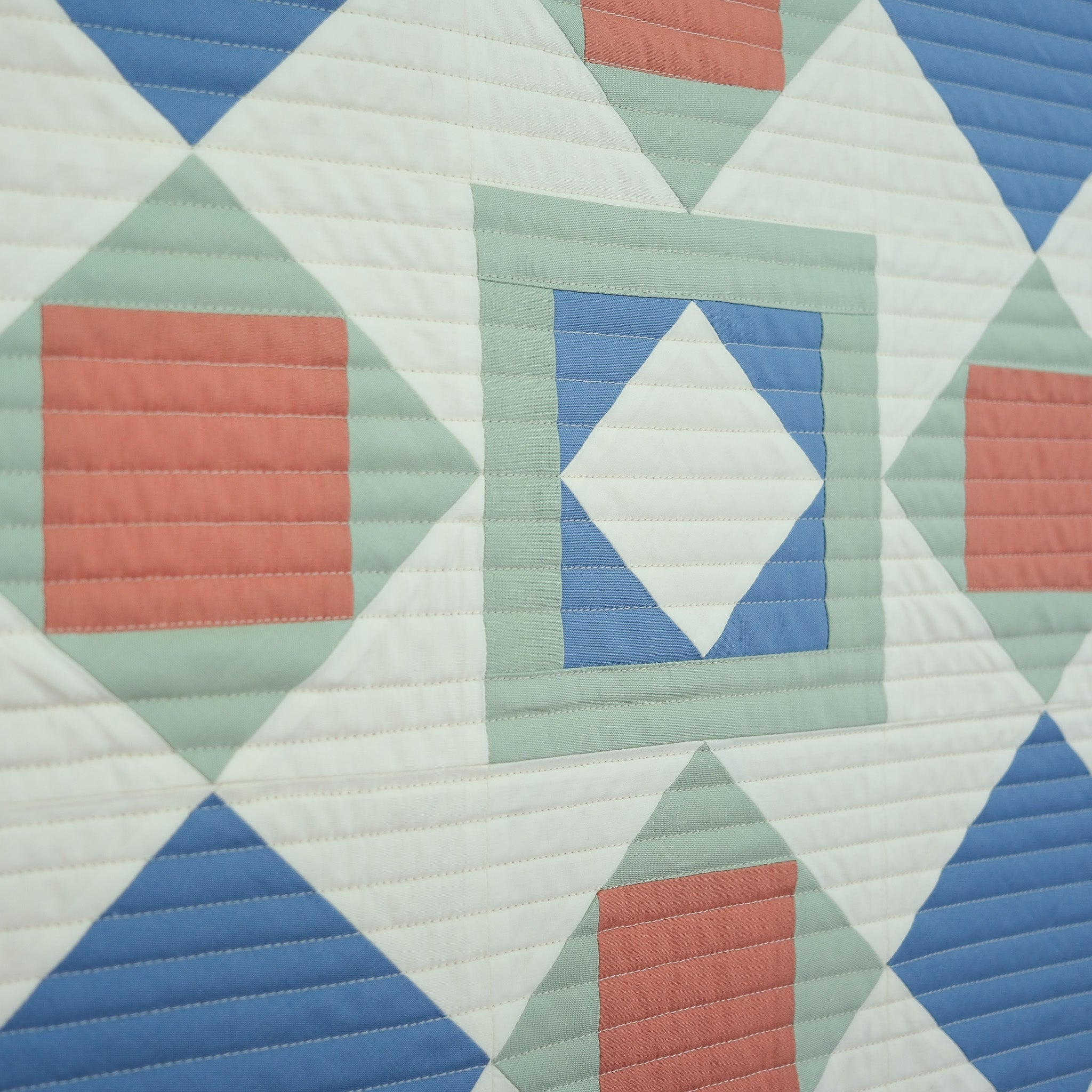 Quilt with geometric pattern featuring triangles and squares in blue, green, and red.