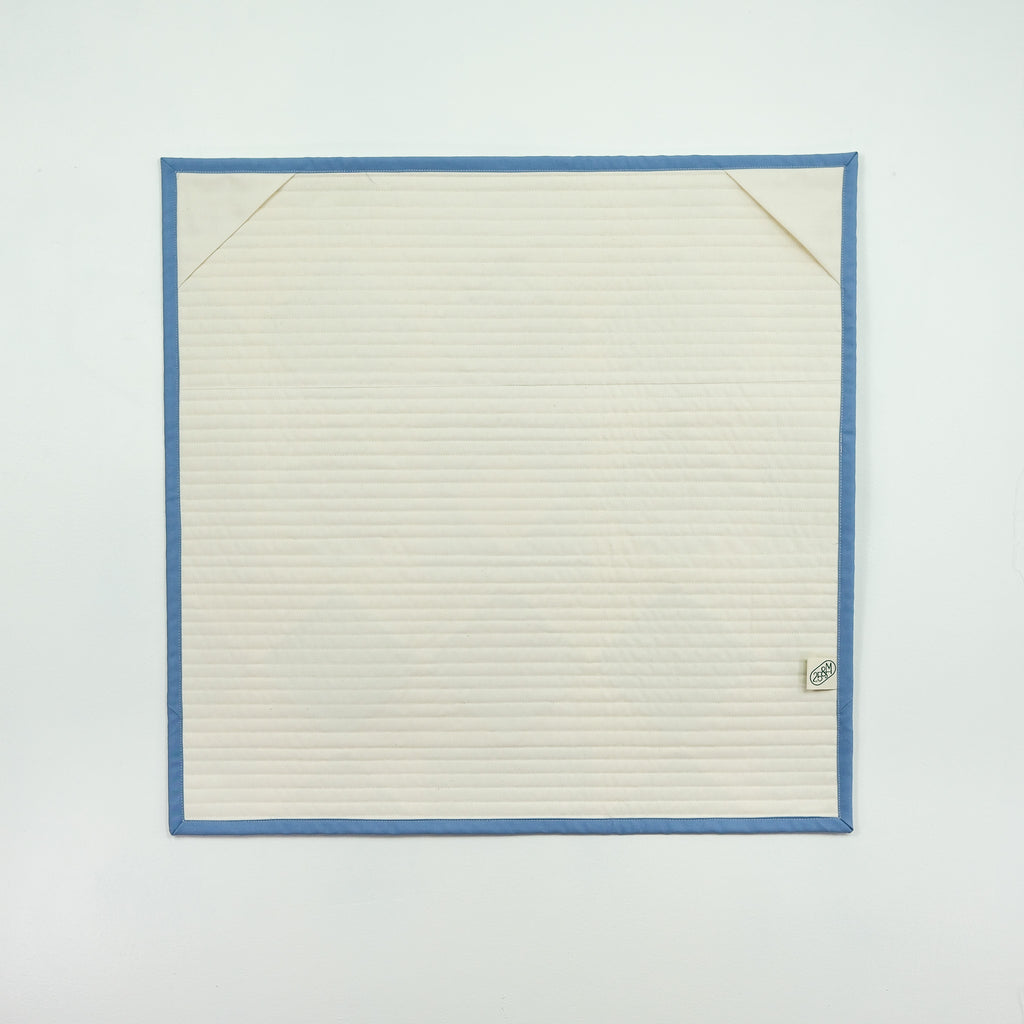 Back of quilt showing white fabric and hanging corner tabs