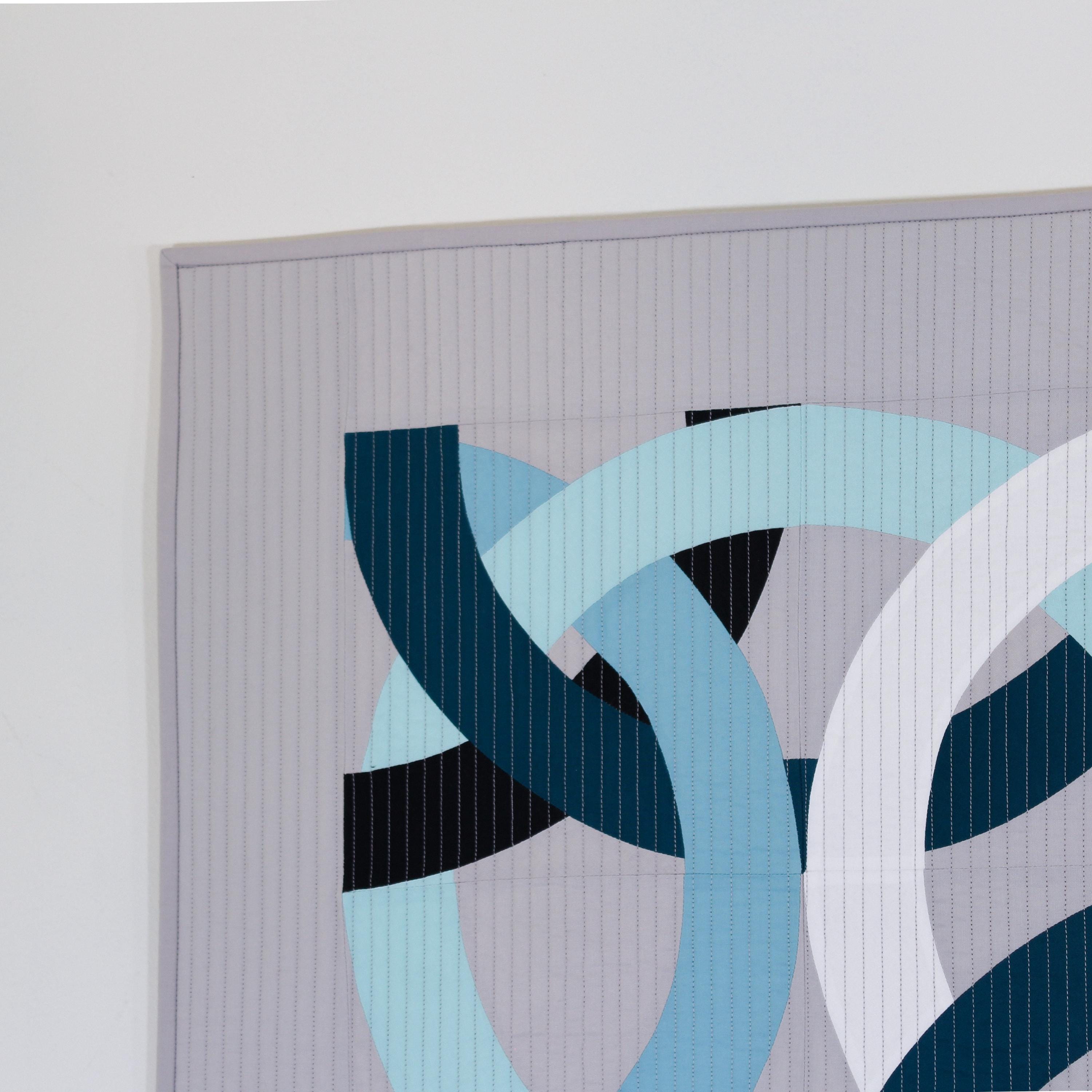 Abstract art piece with interlocking circular shapes in blue, black, and white on a gray background.